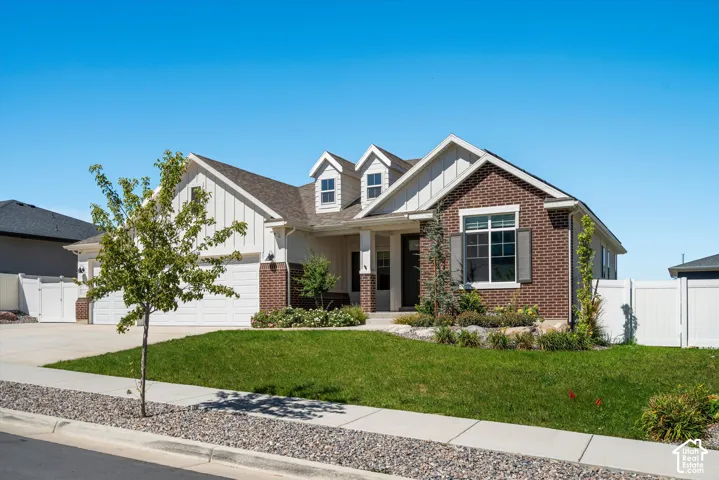 Brick and siding exterior with a multi-car driveway, attached garage, gabled roofline, and front landscaping