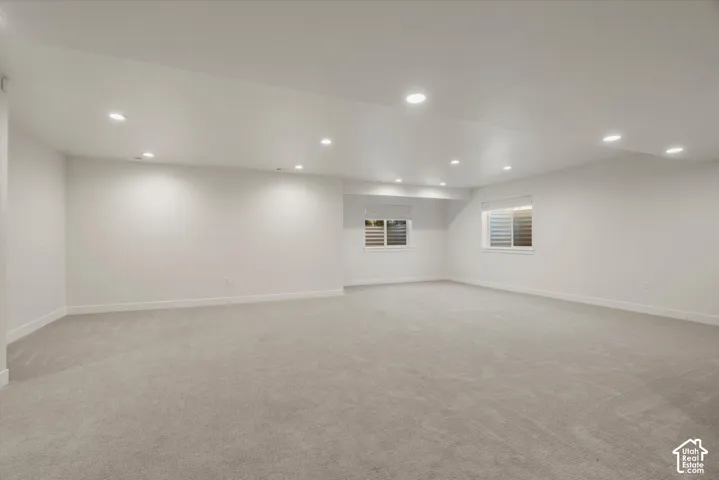 Expansive room featuring recessed lighting, light-toned carpeting, and multiple windows with horizontal blinds
