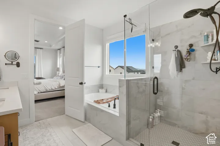 Bathroom featuring vanity, a garden tub, a shower stall, light colored carpet, and ensuite bath
