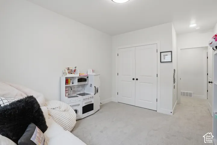 Bedroom with light colored carpet and a closet