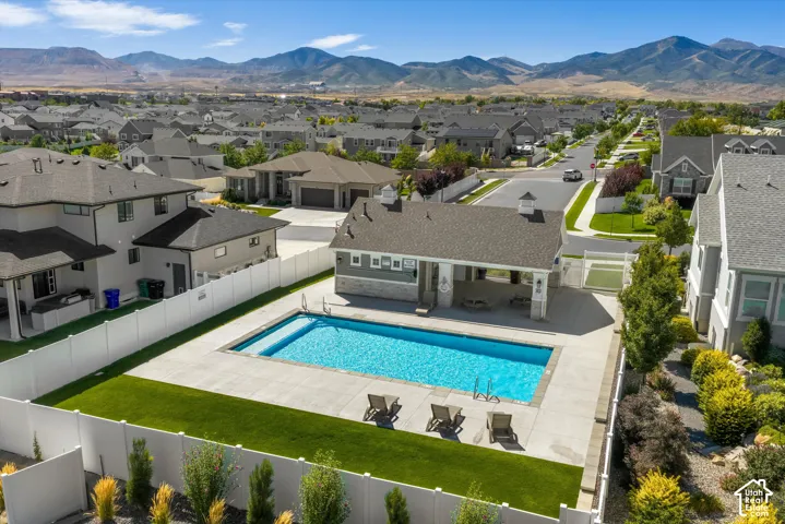 Community pool with a covered patio and concrete surround, surrounded by a white privacy fence and manicured lawn