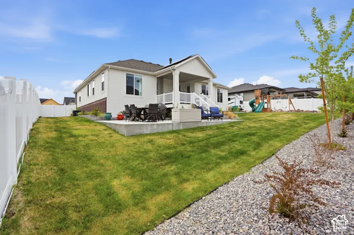 Rear view of property with a patio area, a fenced backyard, a playground, outdoor dining area, and stucco siding
