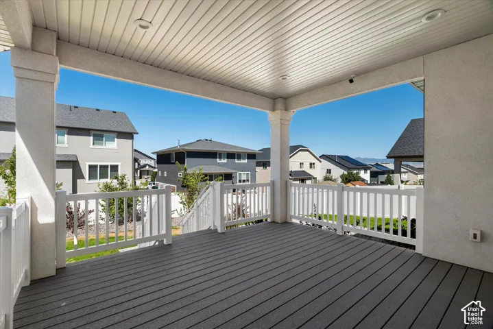 Covered patio featuring composite decking, white railing, and recessed lighting