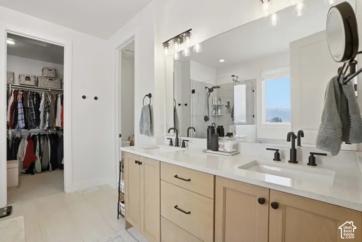 Full bathroom featuring double vanity, a stall shower, and a walk in closet