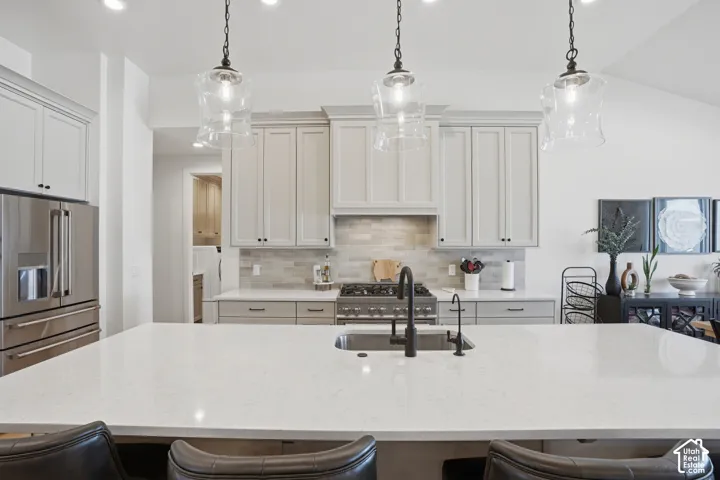 Kitchen featuring a breakfast bar, stainless steel appliances, decorative backsplash, and light stone countertops