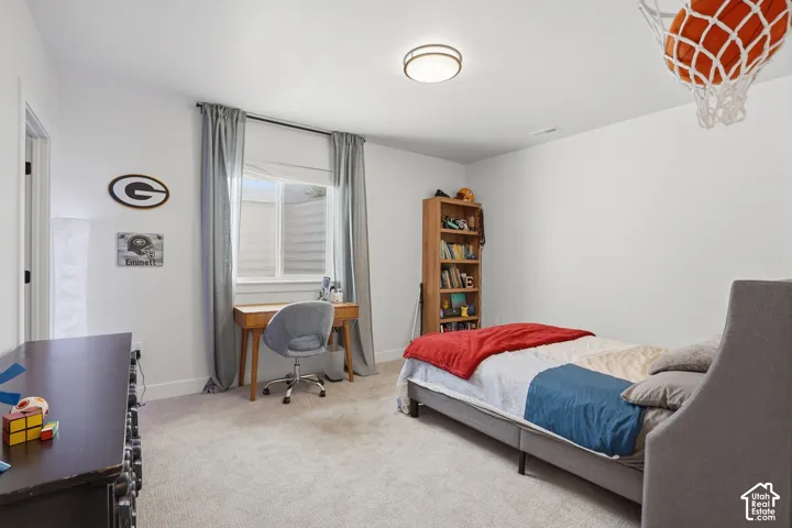 Bedroom featuring light carpet and an office area