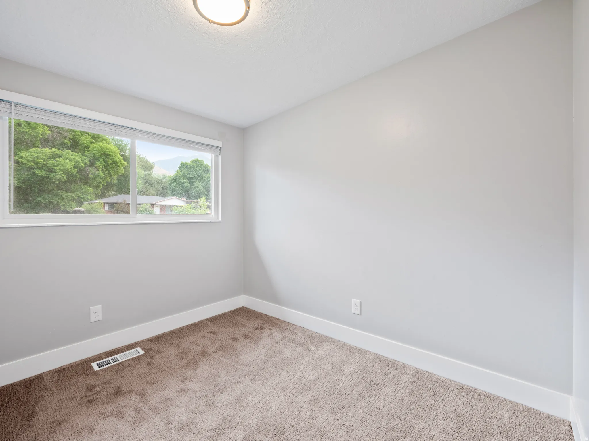 Spare room featuring baseboards and light colored carpet