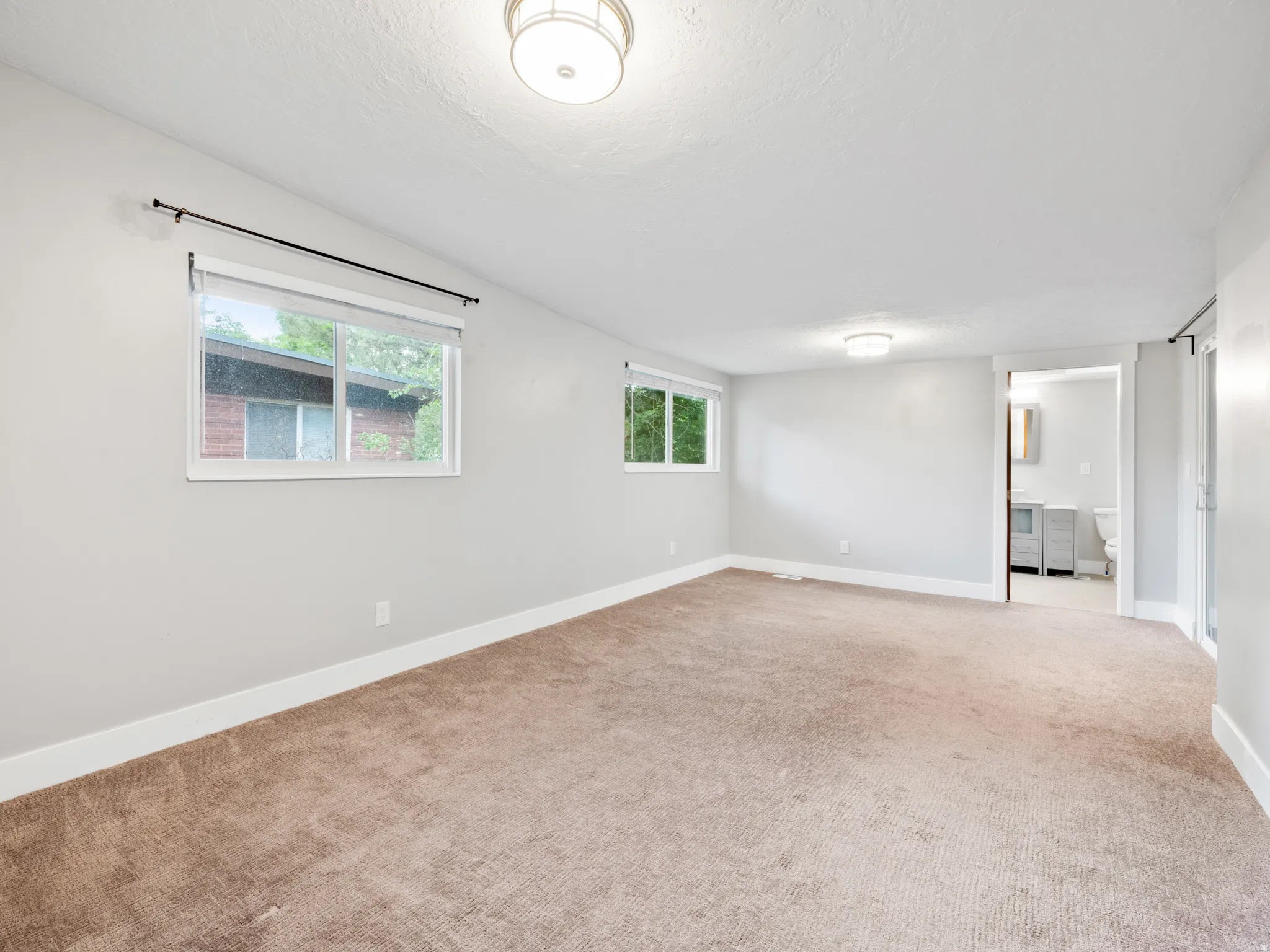 Empty room featuring light colored carpet and a textured ceiling