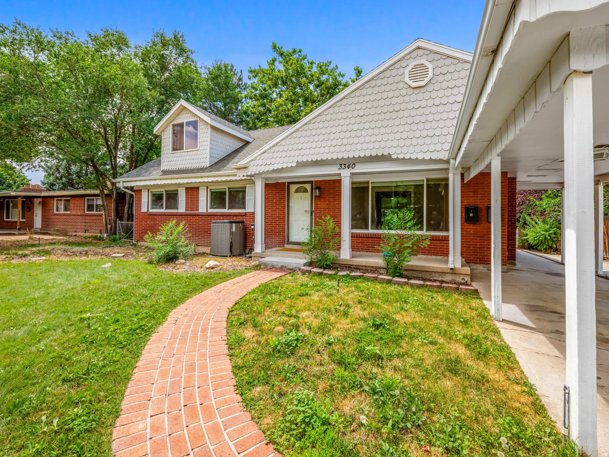 View of front of property featuring a front lawn, covered porch, and brick siding