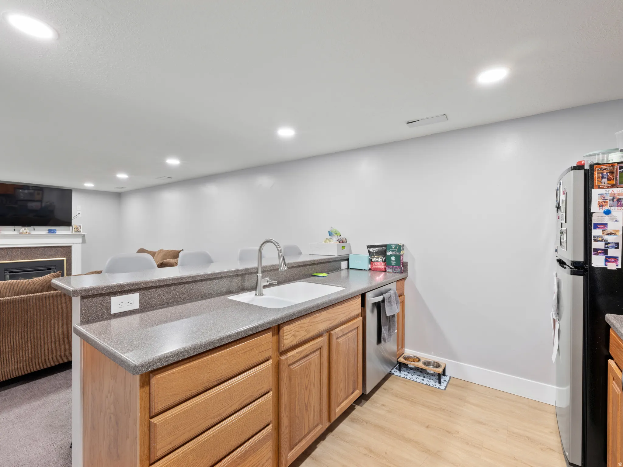 Kitchen featuring open floor plan, a peninsula, stainless steel appliances, recessed lighting, and light wood-style floors