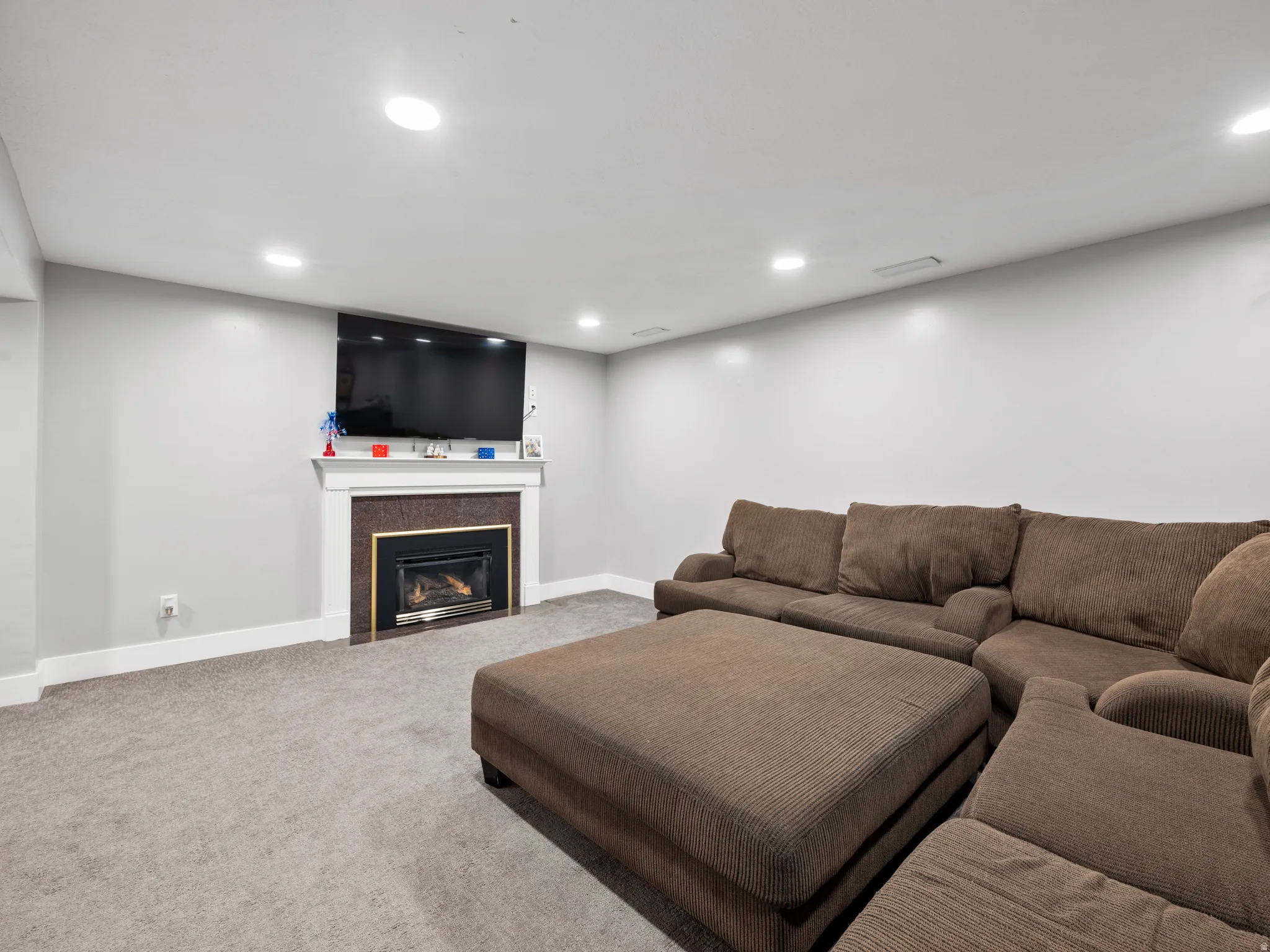 Living area with a glass covered fireplace, carpet flooring, and recessed lighting