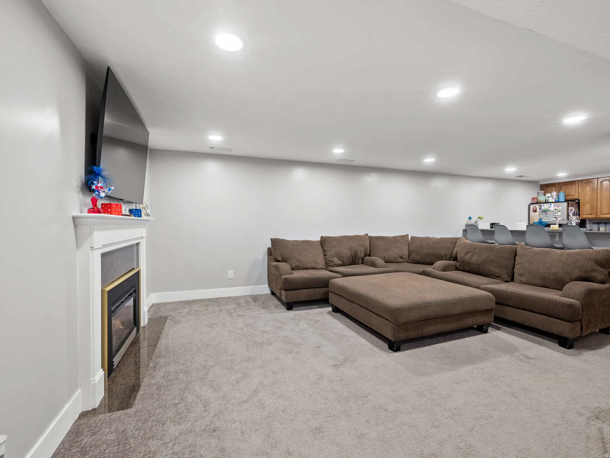 Living area with recessed lighting, light carpet, and a glass covered fireplace
