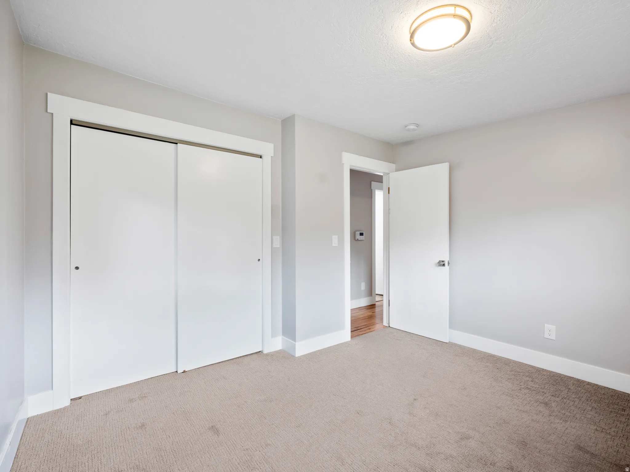 Unfurnished bedroom with light carpet and a closet