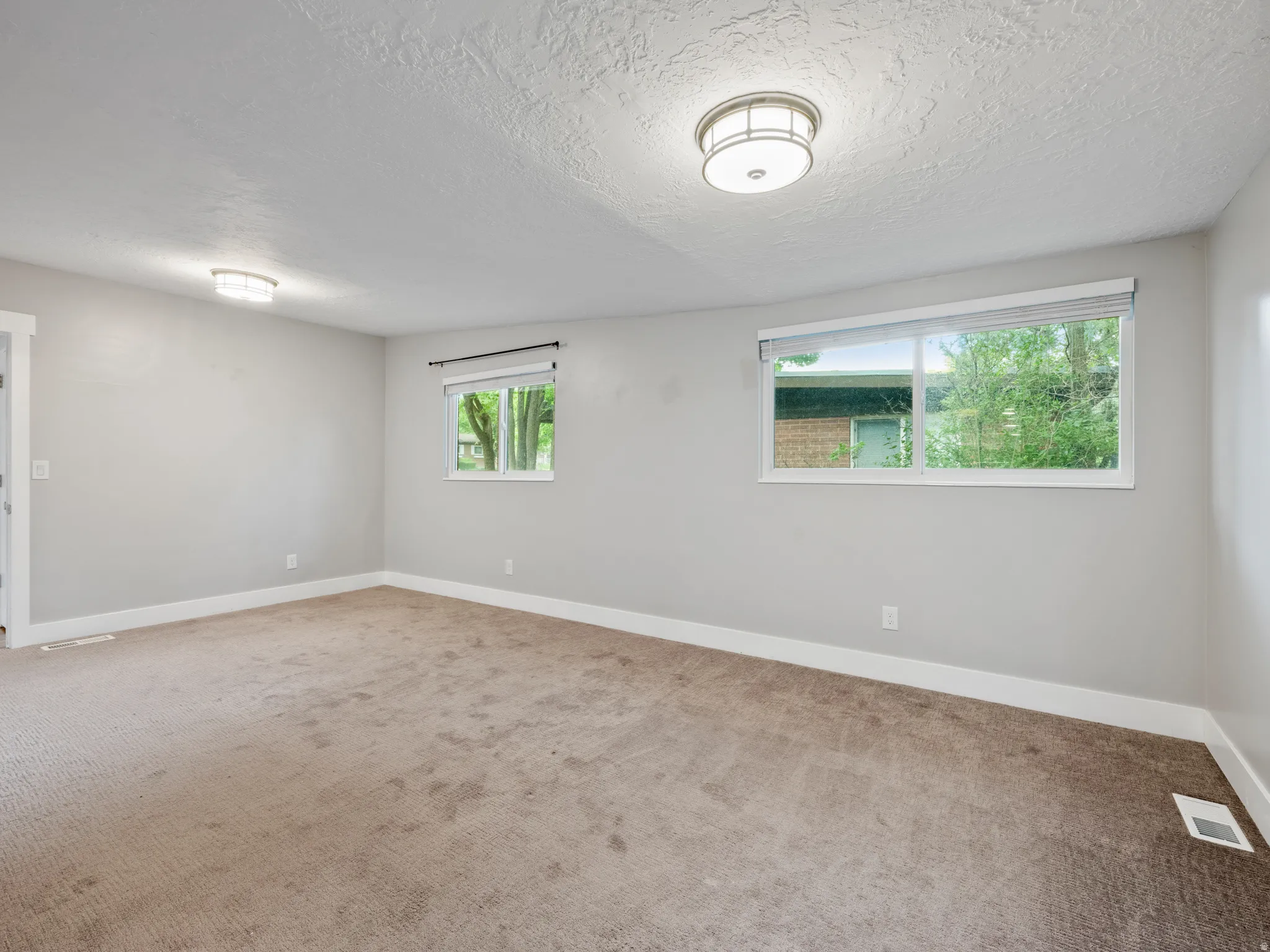 Unfurnished room with a textured ceiling and light carpet
