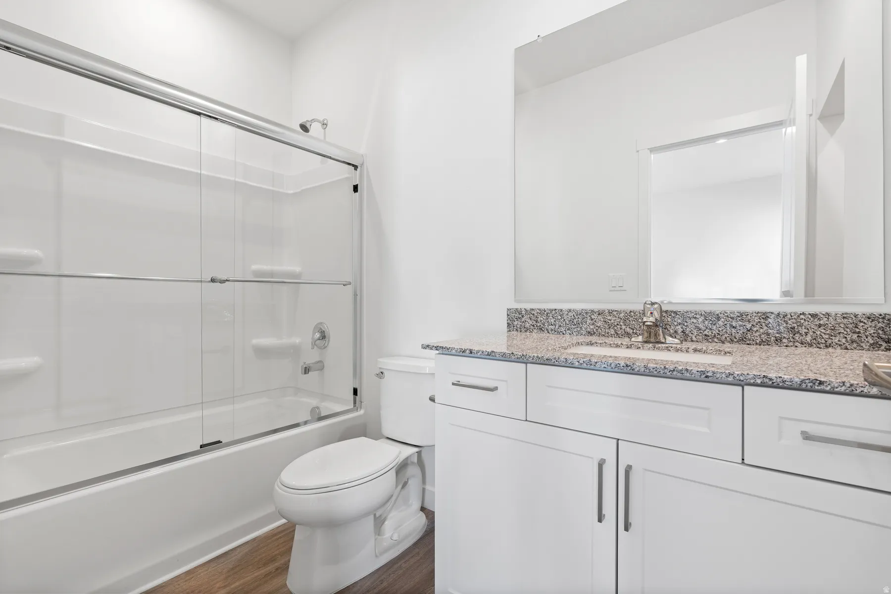Full bath with vanity, dark wood-style flooring, and shower / bath combination with glass door