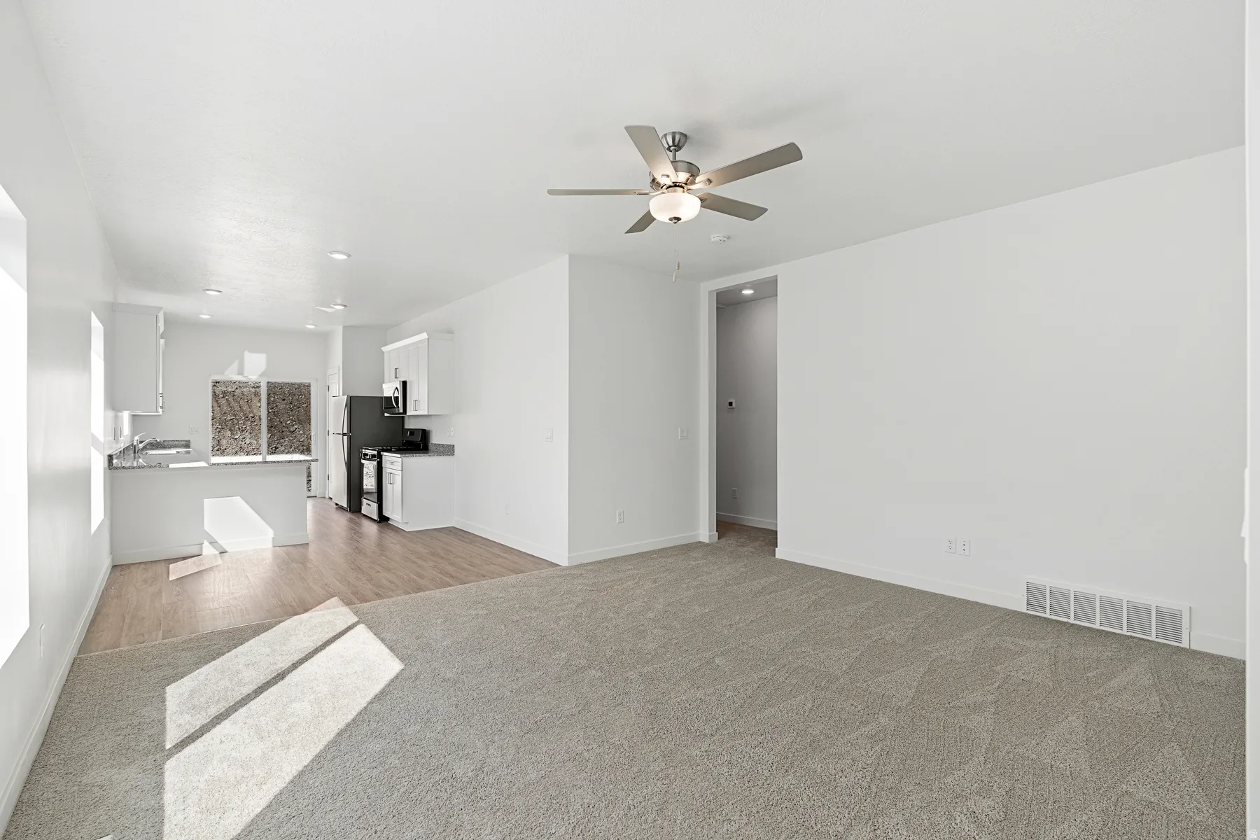 Unfurnished living room featuring a ceiling fan, light carpet, and recessed lighting
