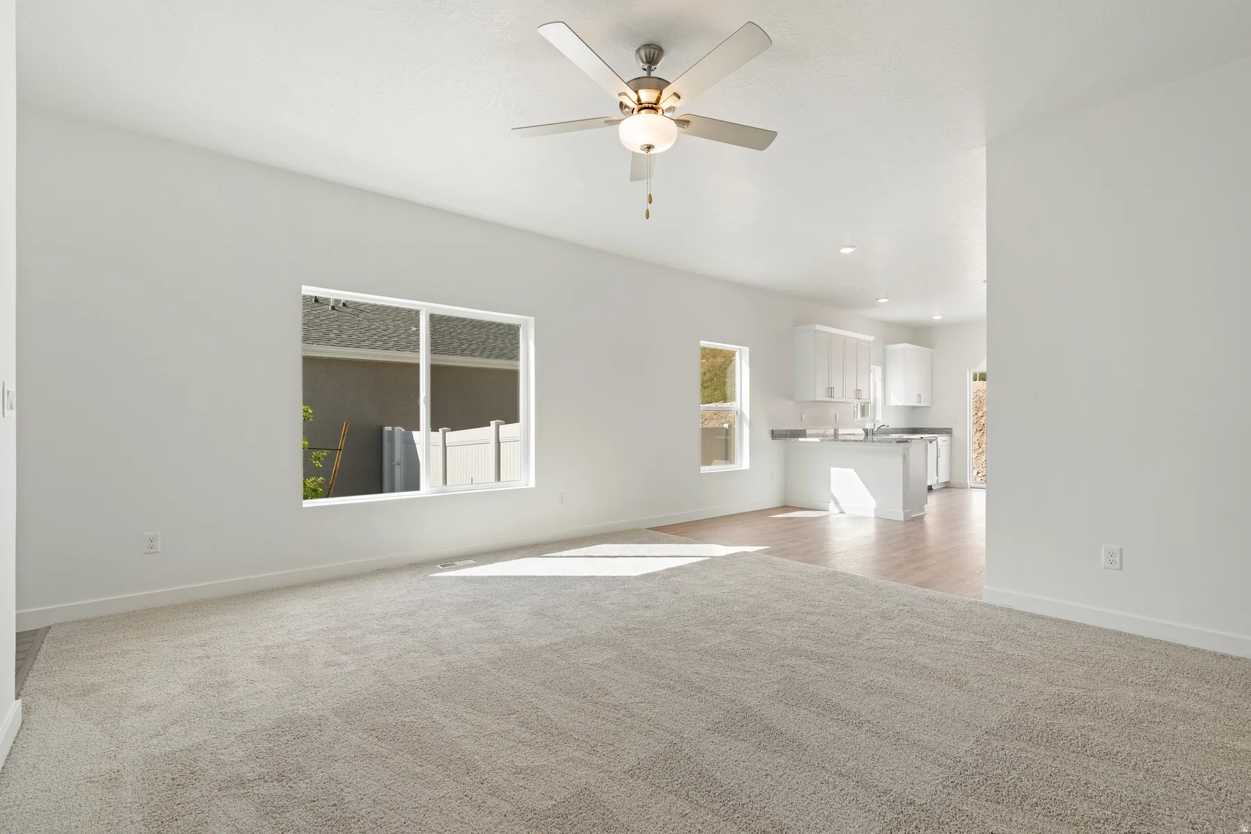Unfurnished living room with light colored carpet and ceiling fan