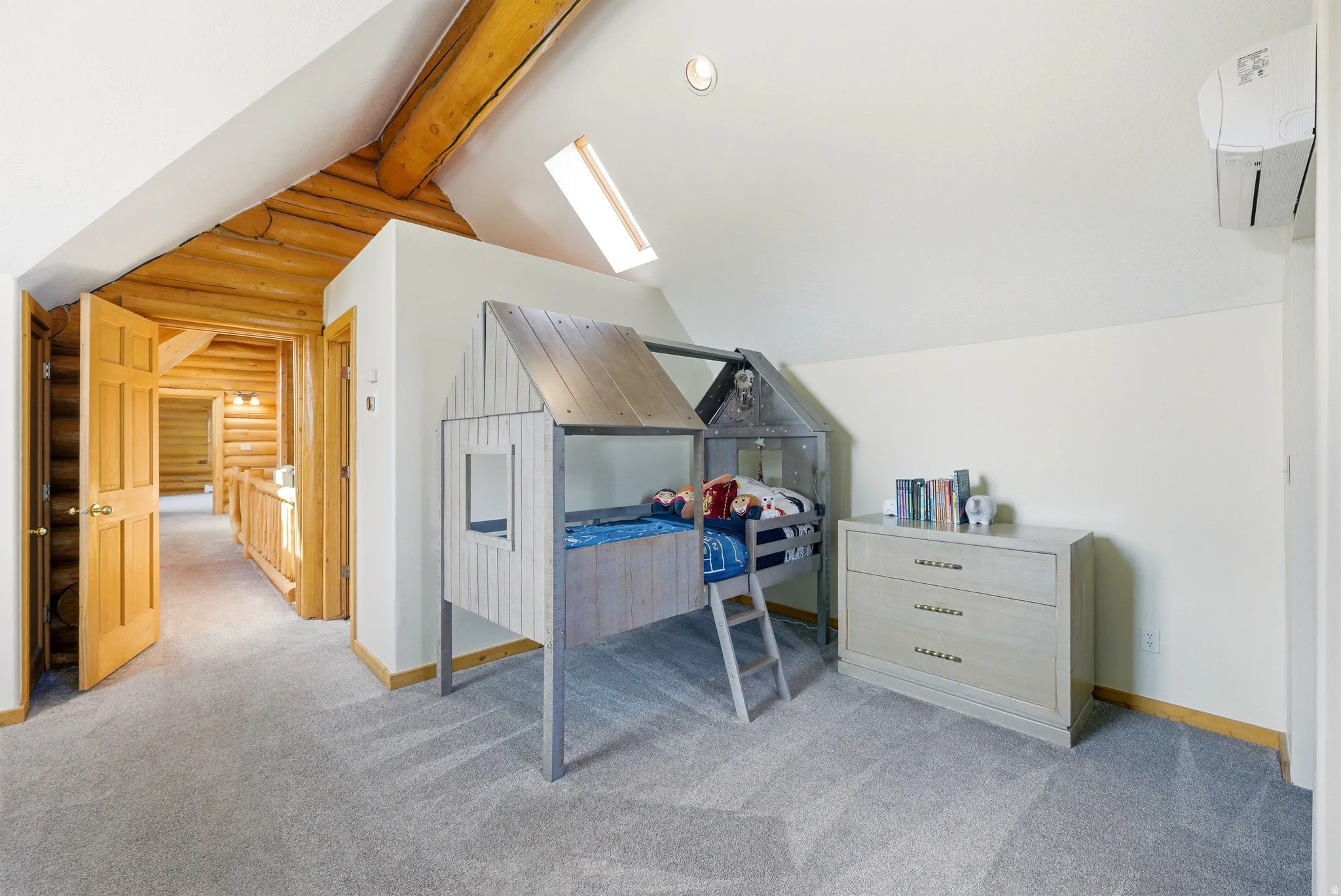Bedroom featuring log walls, light carpet, vaulted ceiling with beams, and a skylight