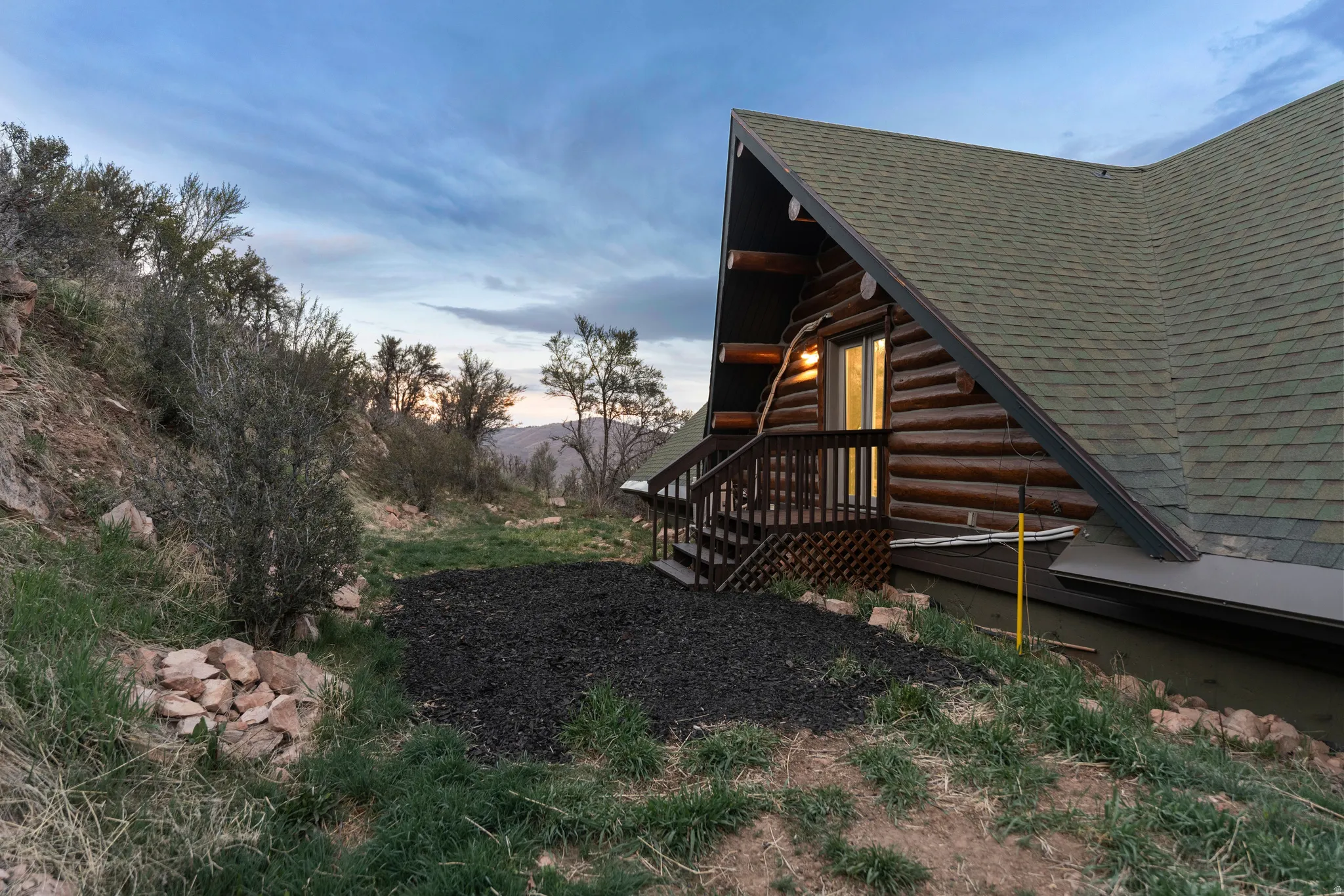 View of side of home with a shingled roof, a deck, and log exterior