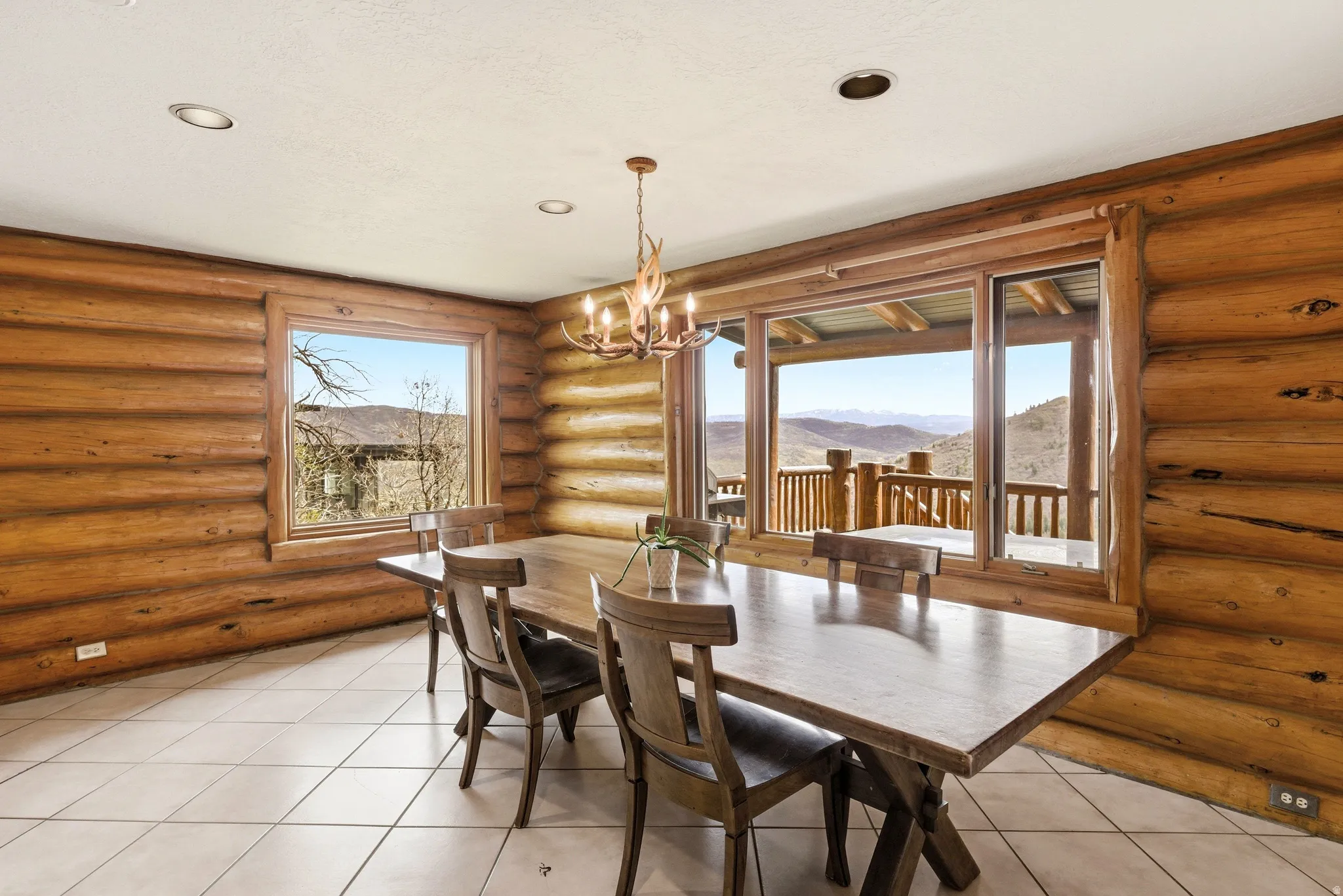 Dining room featuring log walls, a mountain view, a chandelier, and light tile patterned flooring