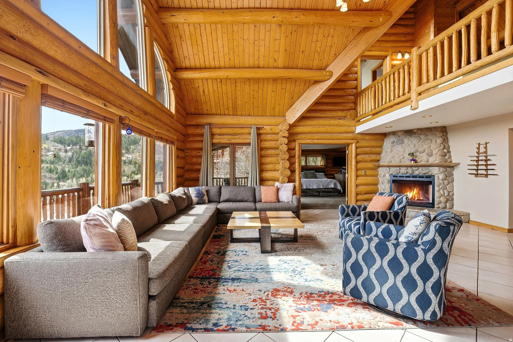 Tiled living room featuring rustic walls, a fireplace, and a high wooden beamed ceiling