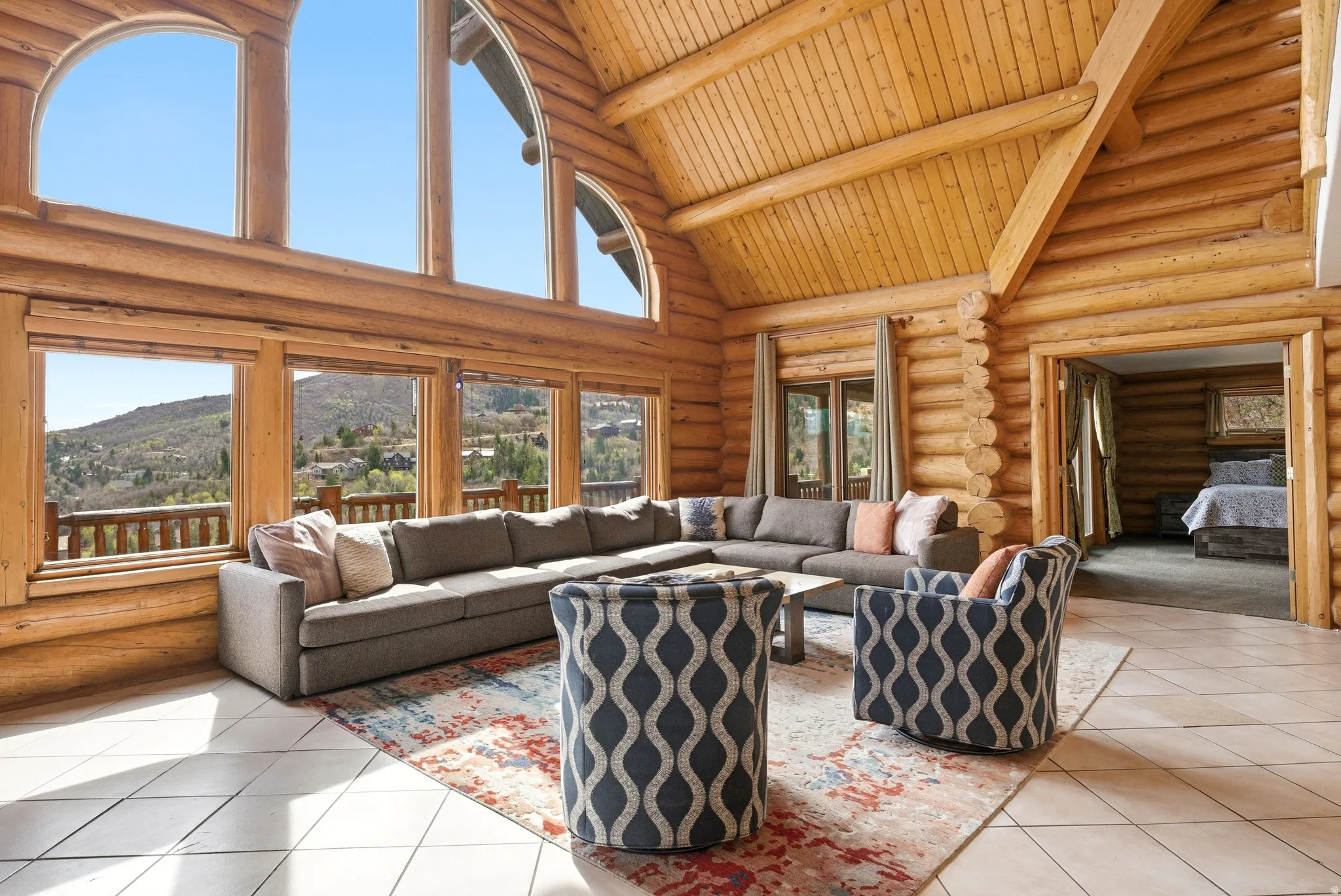 Living room with rustic walls, a mountain view, a high wooden beamed ceiling, and tile patterned floors