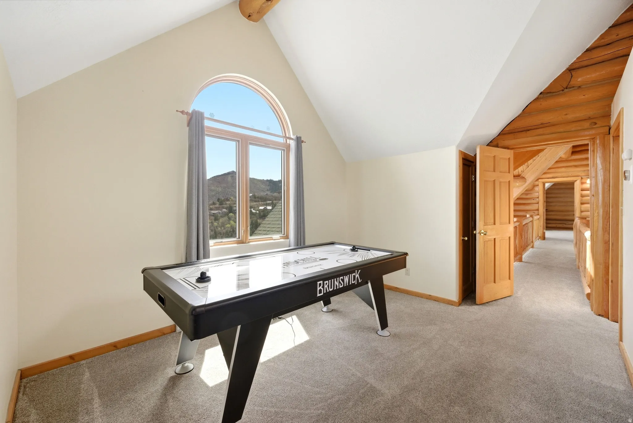 Recreation room featuring light carpet, beamed ceiling, and a mountain view
