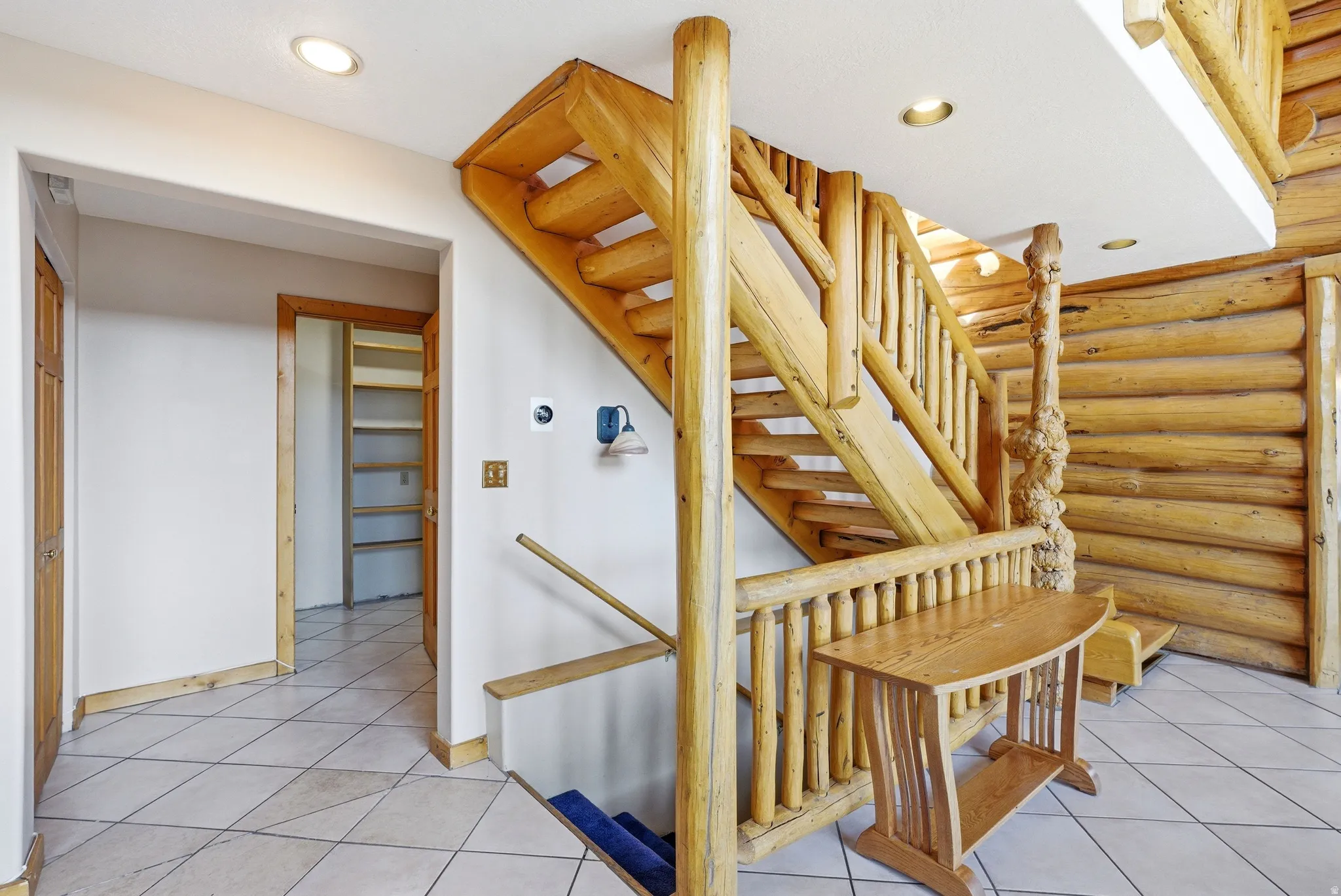Staircase with log walls, tile patterned flooring, and recessed lighting
