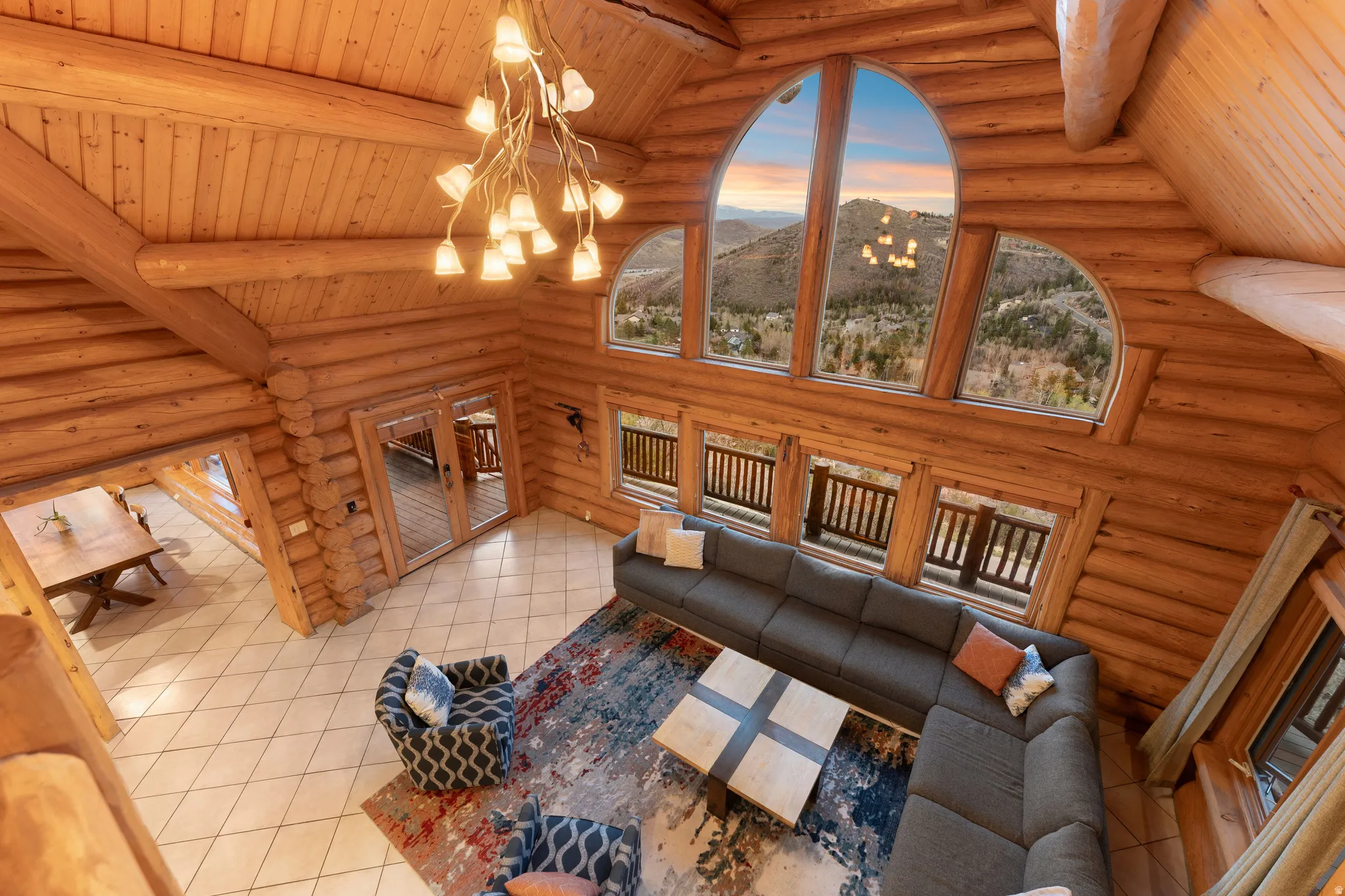 Living room featuring a chandelier, a mountain view, wooden ceiling, log walls, and vaulted ceiling with beams