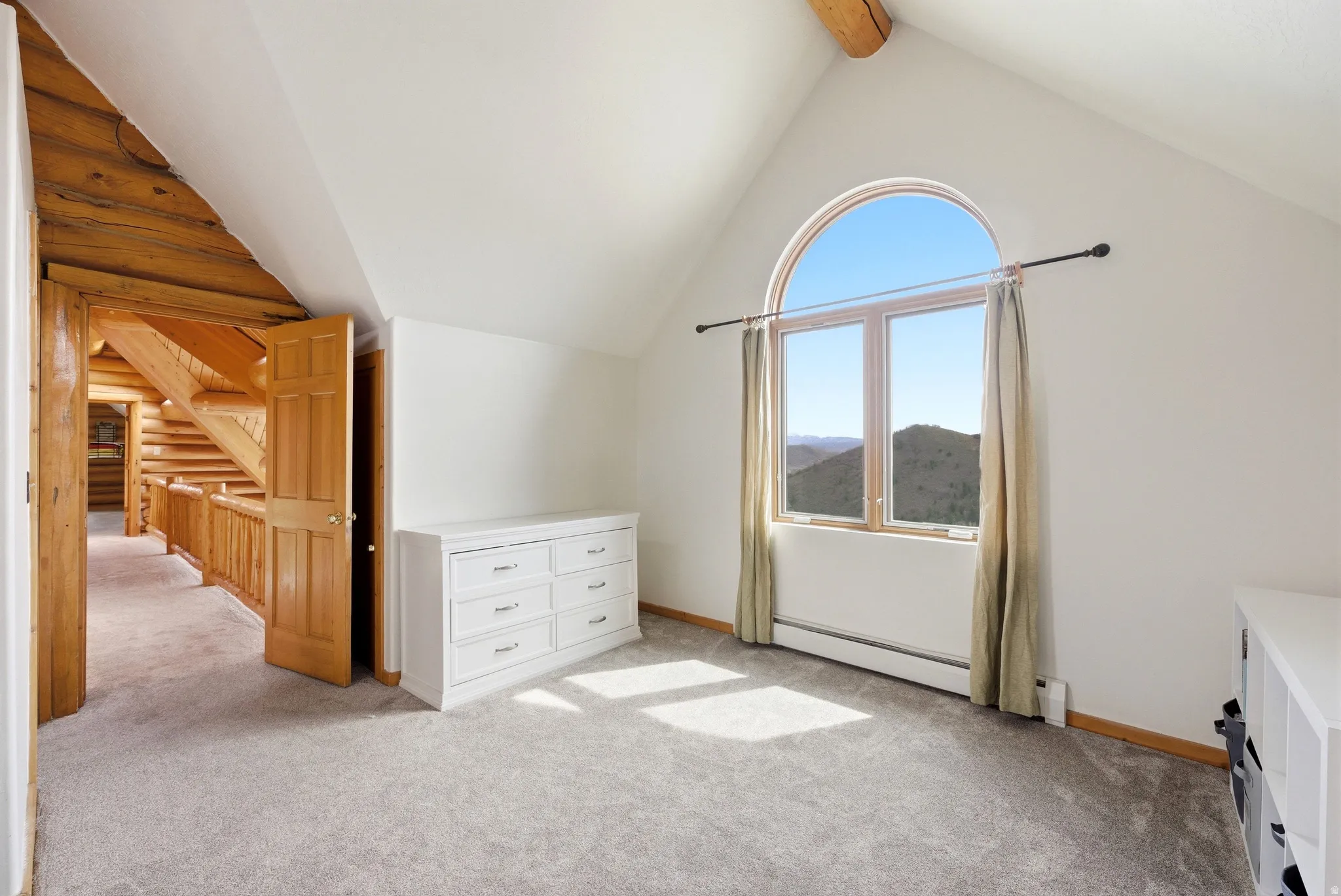 Bonus room with baseboard heating, beam ceiling, light colored carpet, a mountain view, and log walls