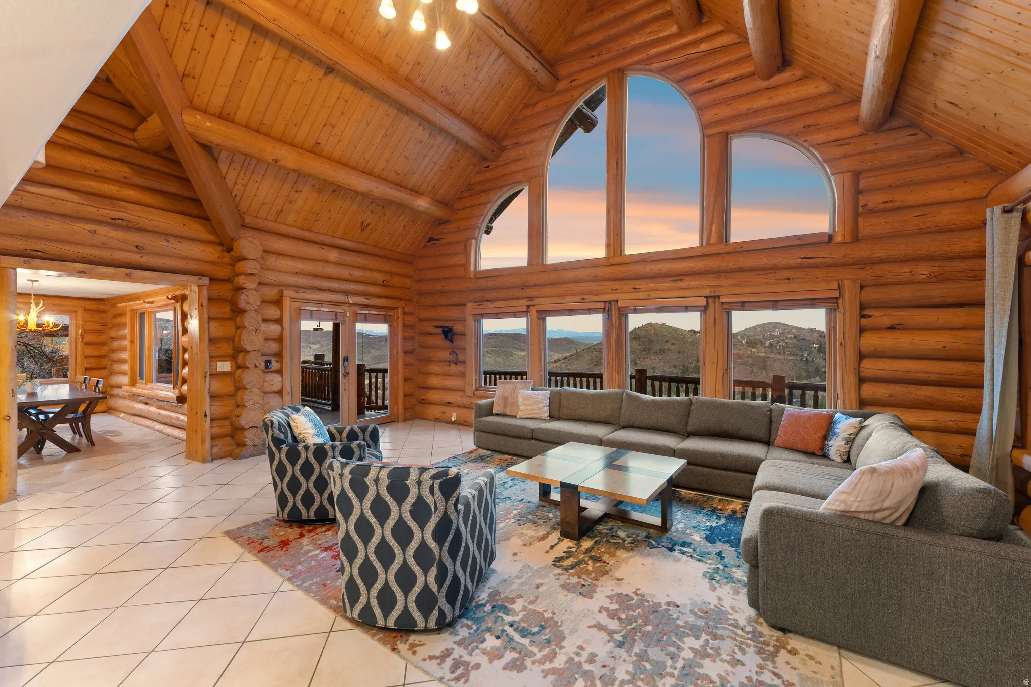 Living area with log walls, a high wood beamed ceiling, hanging lights, a mountain view, and tile patterned floors