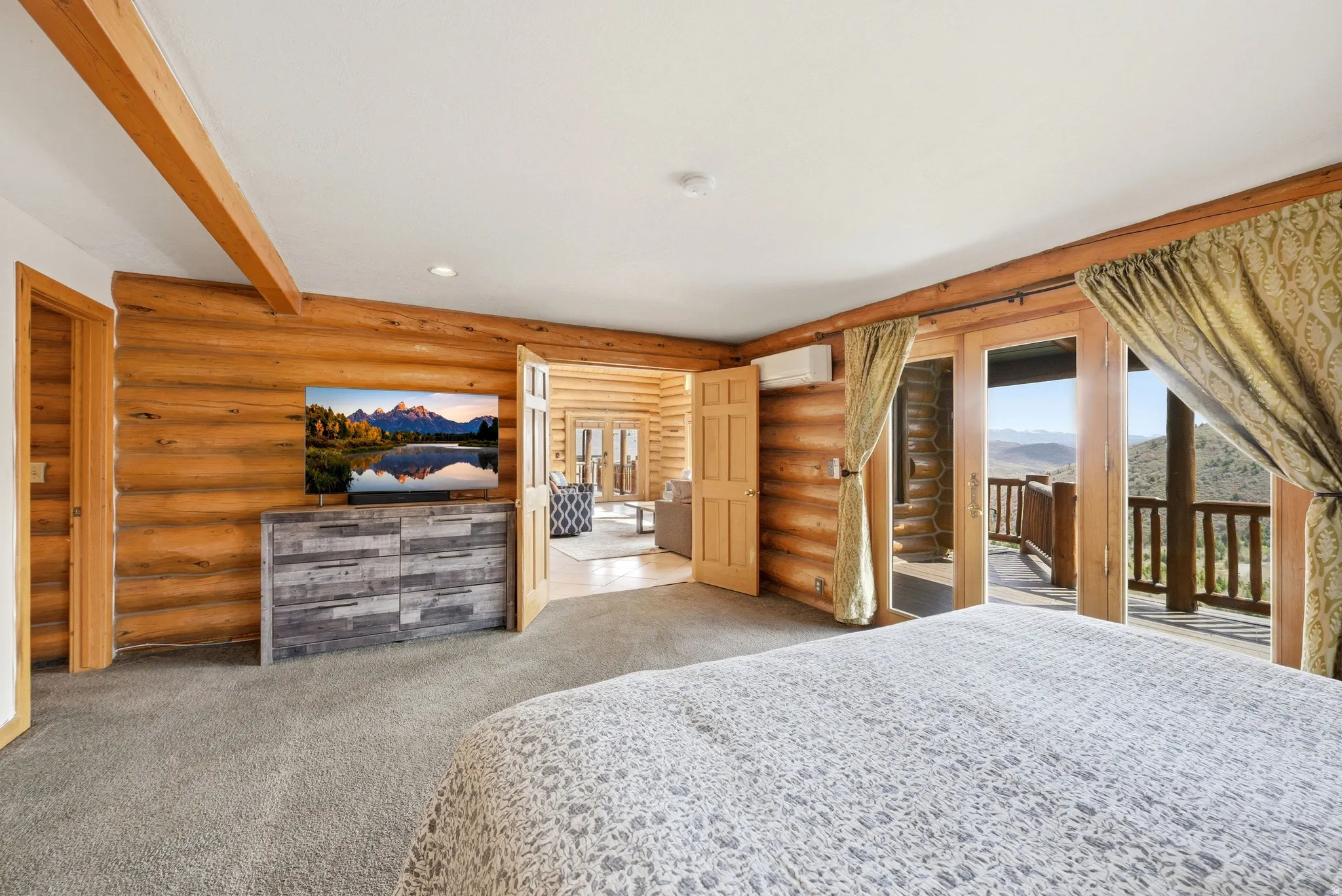 Bedroom with light colored carpet, rustic walls, access to exterior, beam ceiling, and recessed lighting