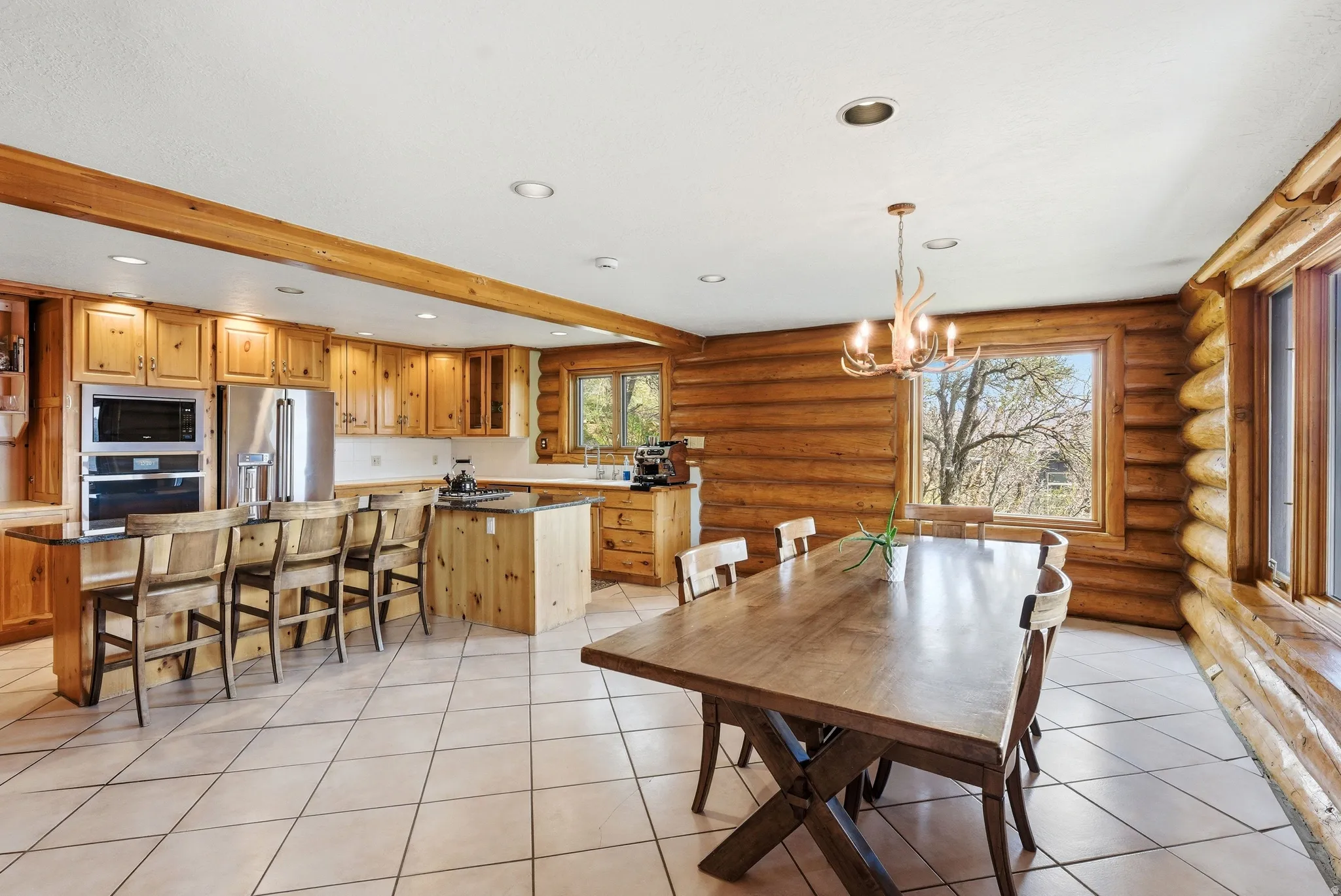 Dining room featuring log walls, hanging lights, and light tile patterned floors