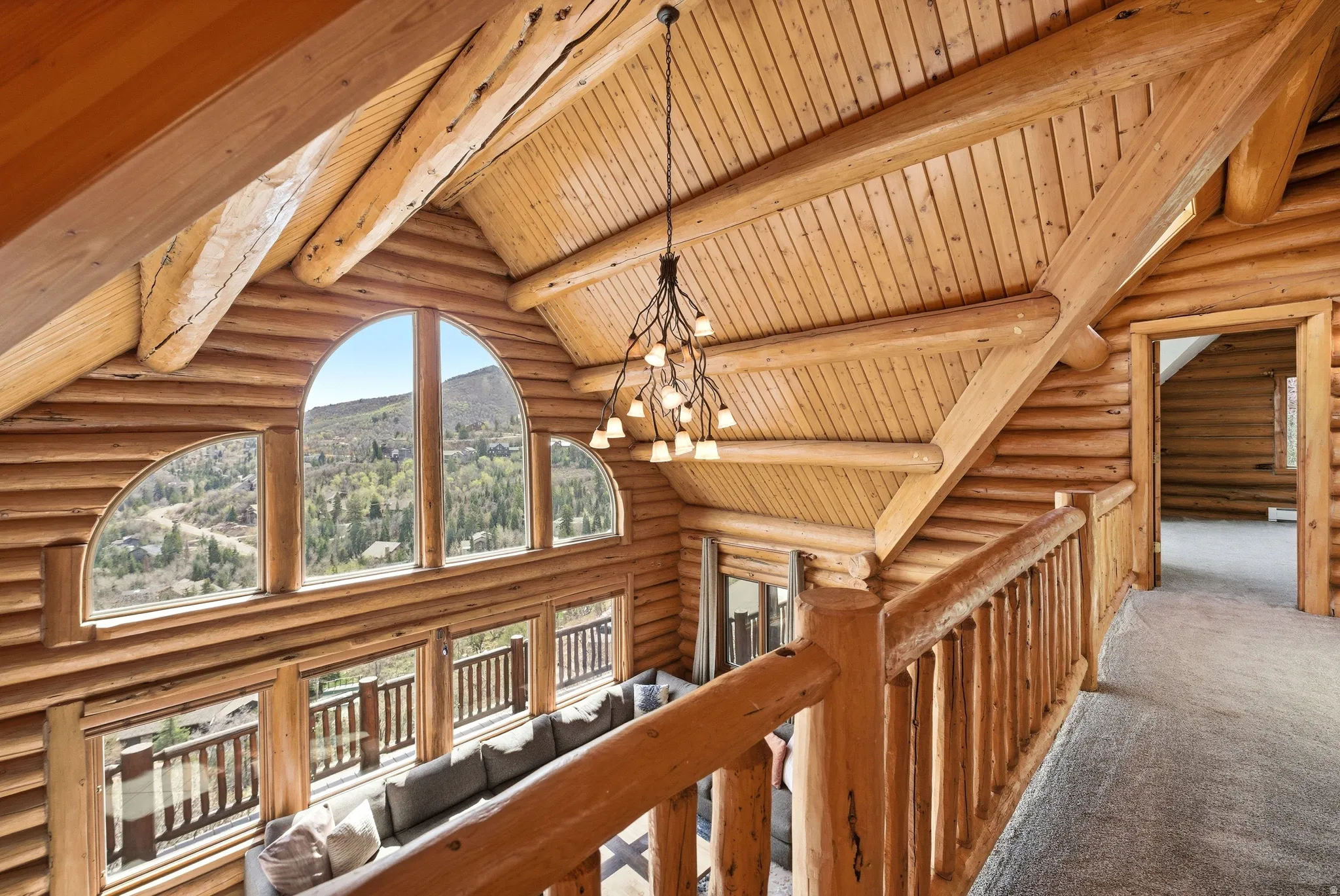 Hall with suspended lighting, log walls, carpet, a high wooden beamed ceiling, and a mountain view