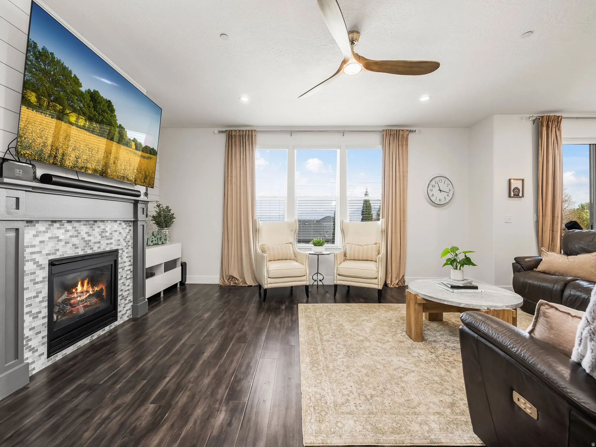 Living area with ceiling fan, dark wood-type flooring, a fireplace, and recessed lighting