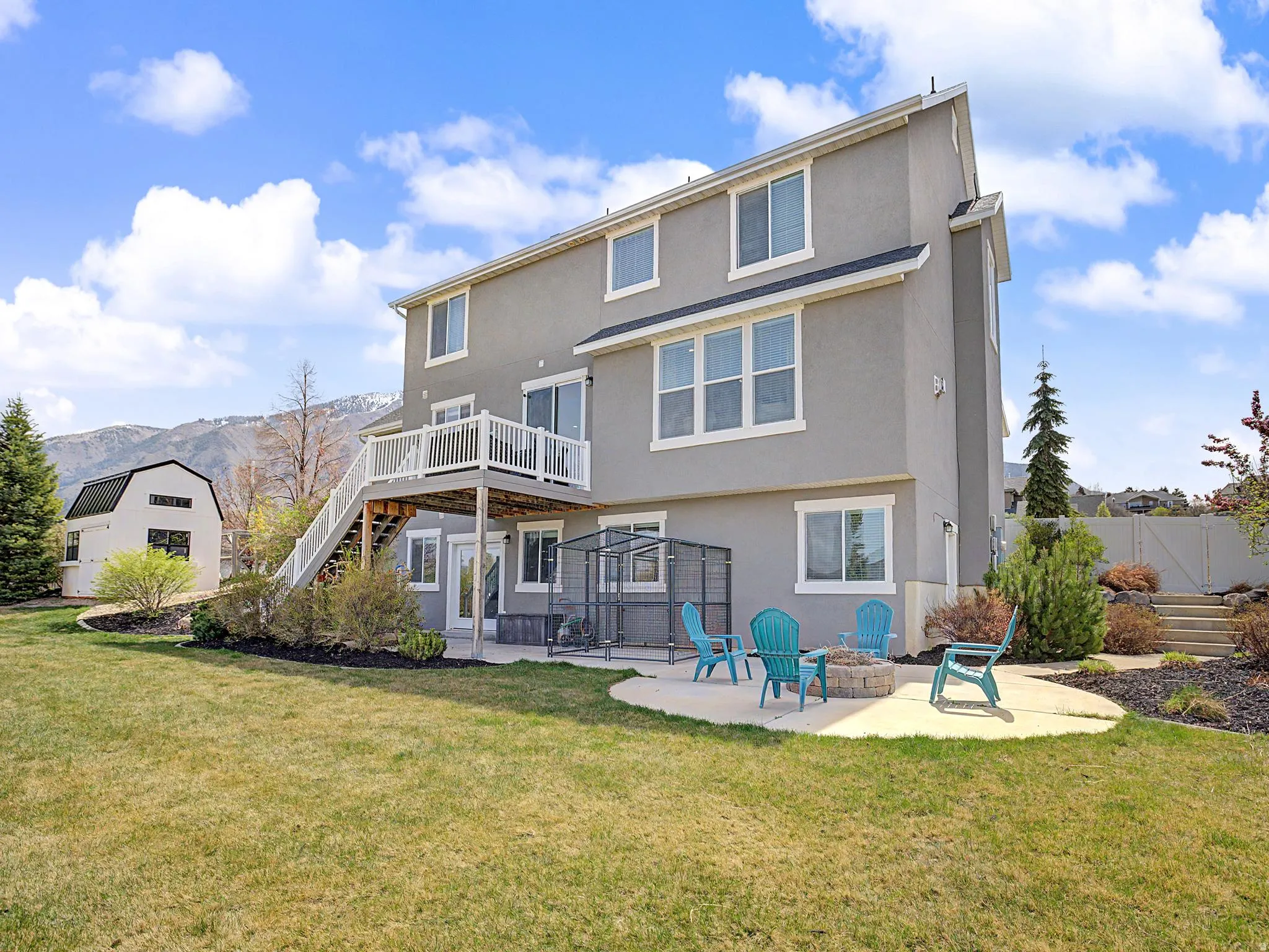 Rear view of property featuring a patio area, stucco siding, a lawn, and a fire pit