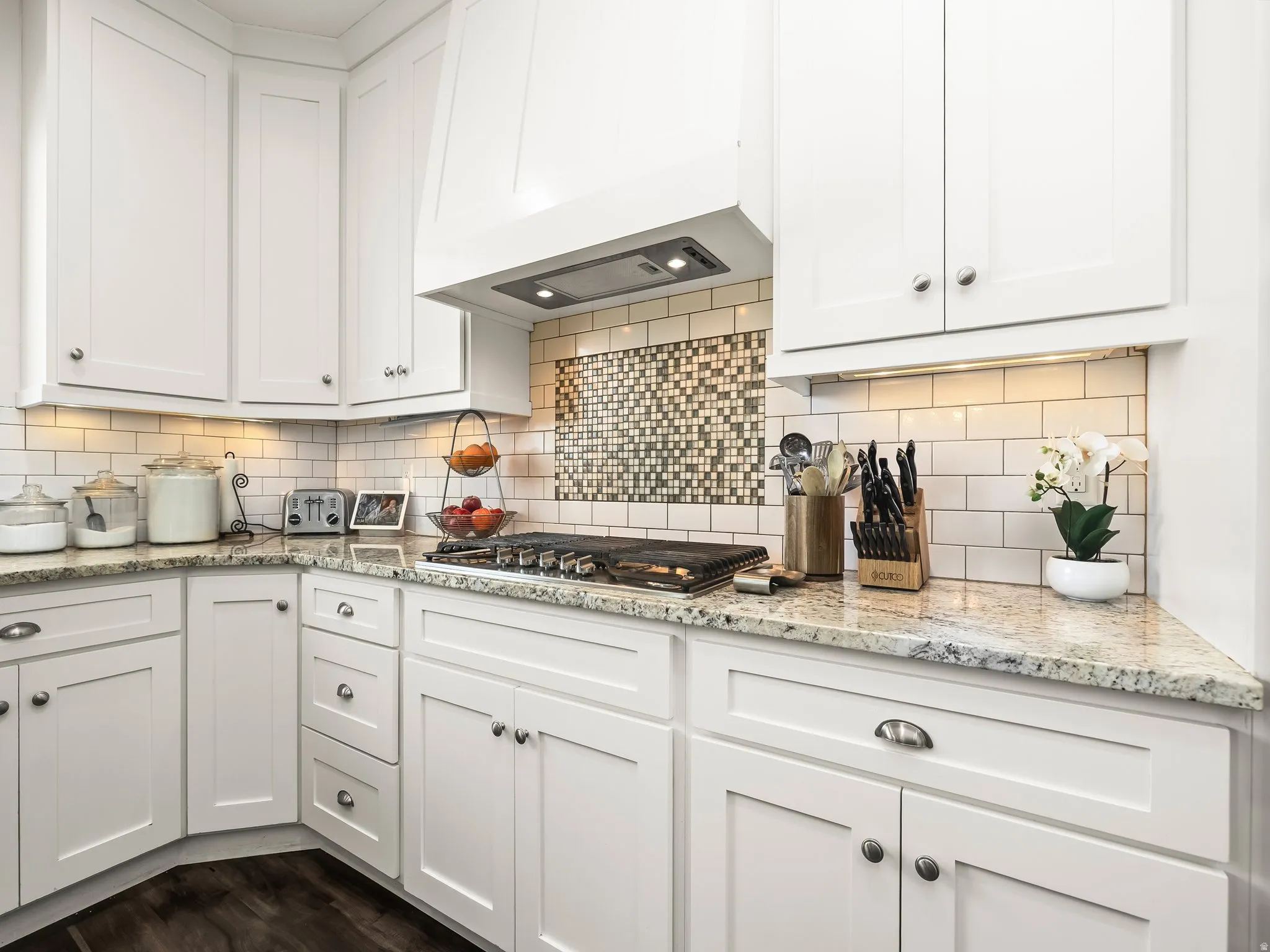Kitchen with white cabinetry, light stone counters, and stainless steel gas stovetop