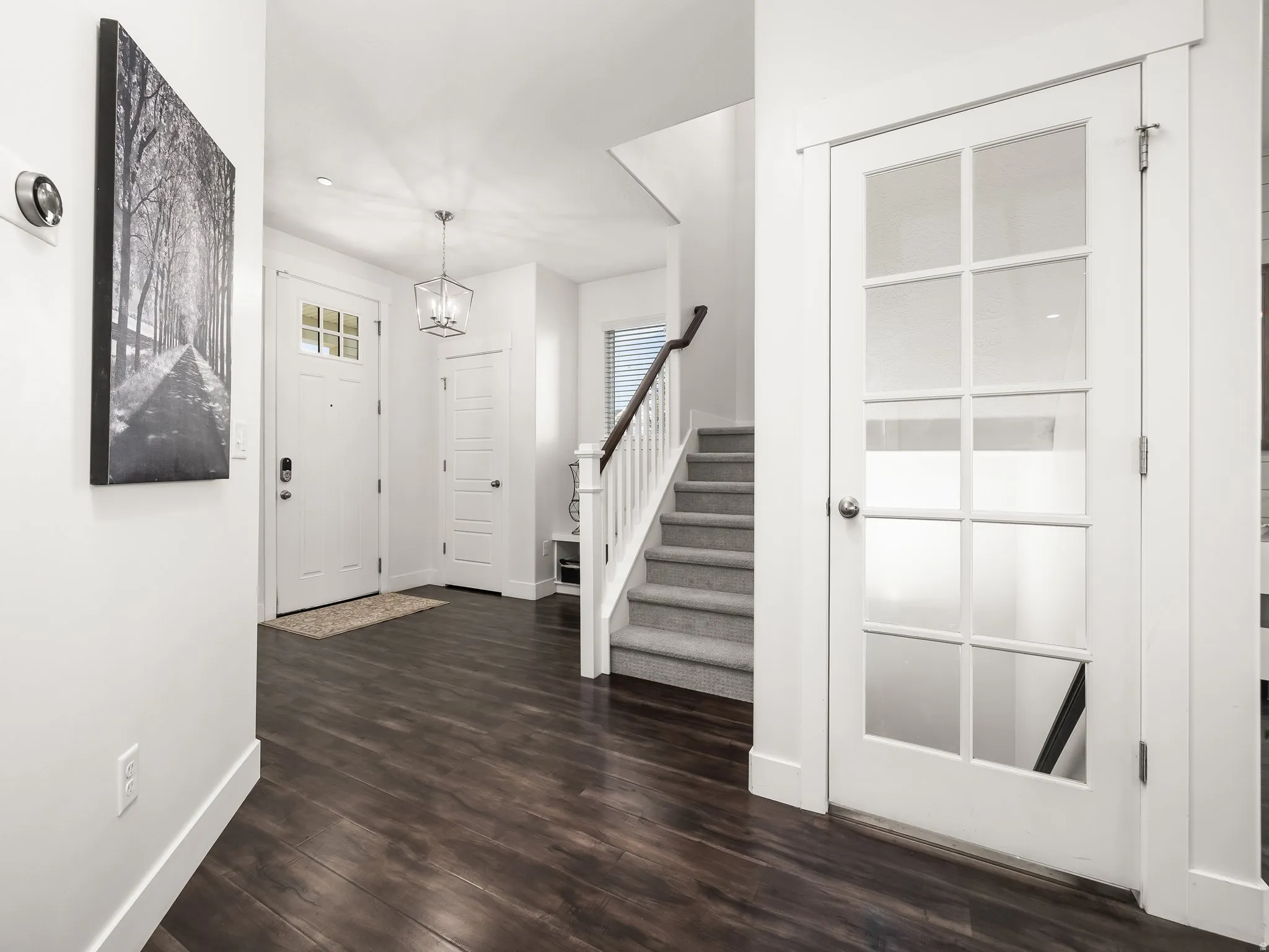 Entryway with dark wood-style flooring and suspended lighting
