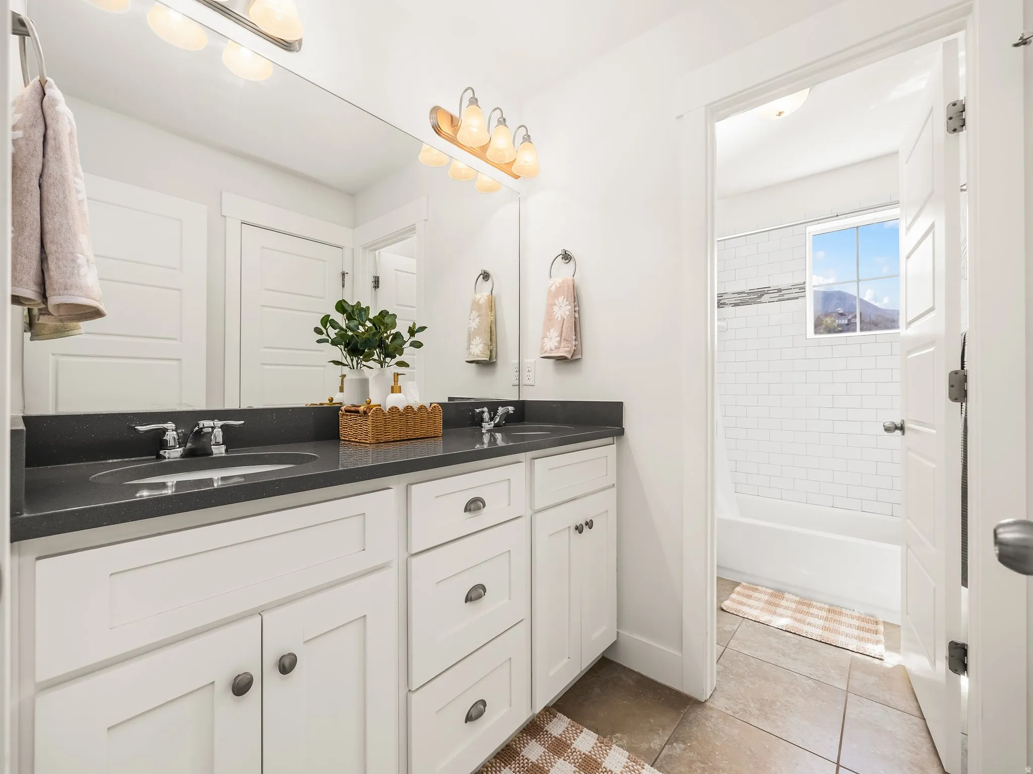 Full bath with double vanity, bathtub / shower combination, and light tile patterned flooring