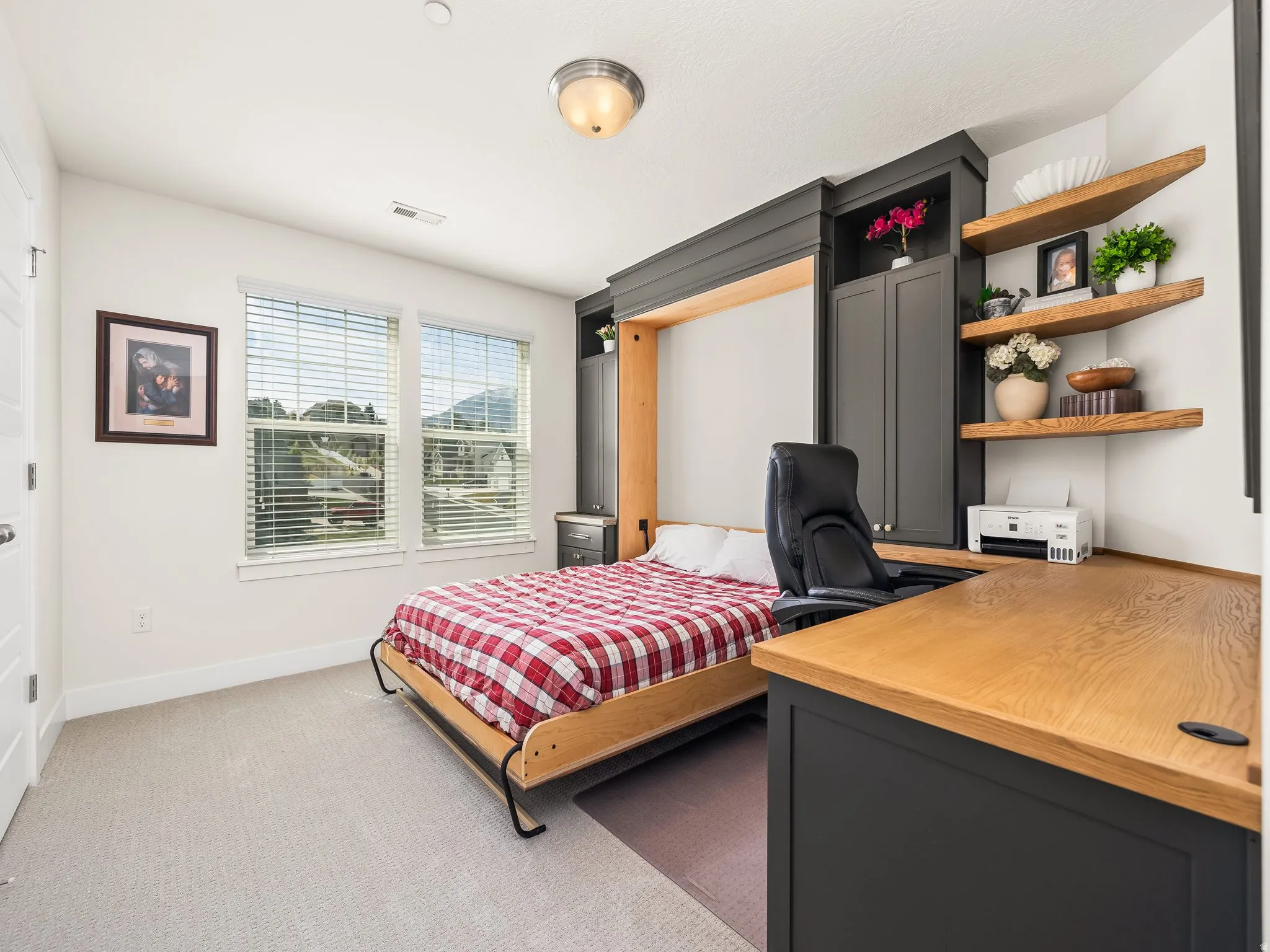 Bedroom featuring light colored carpet and a desk