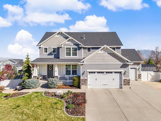 Craftsman-style home featuring a porch, an attached garage, driveway, and stone siding