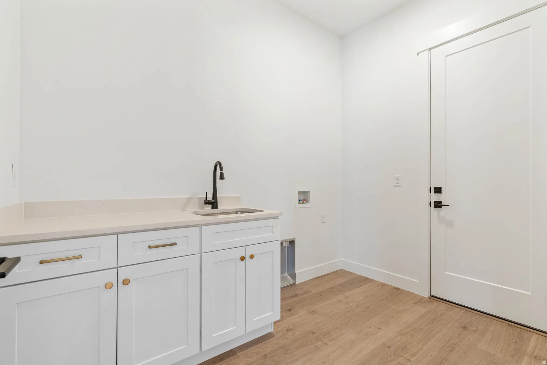 Laundry room with light wood-style flooring, washer hookup, and cabinet space