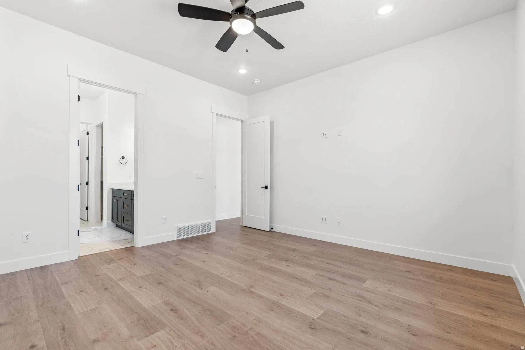 Unfurnished bedroom with ceiling fan, light wood-type flooring, ensuite bathroom, and recessed lighting