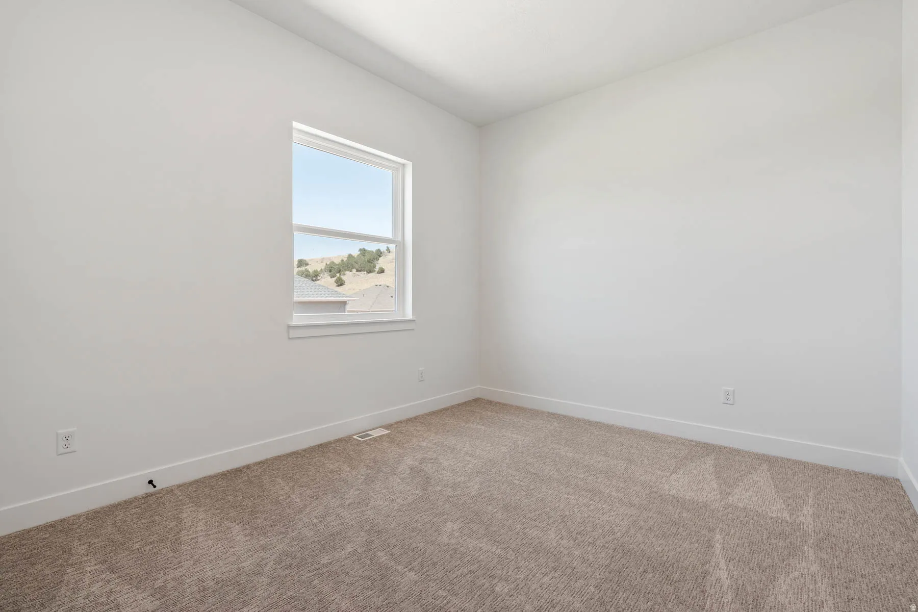Carpeted spare room featuring baseboards