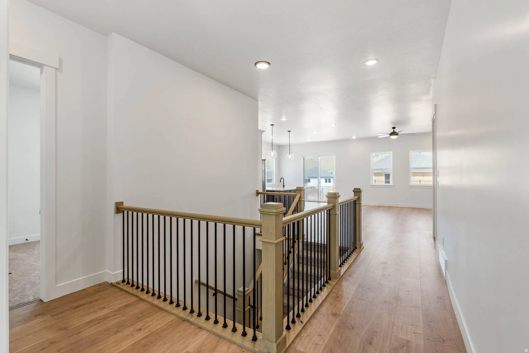 Corridor featuring an upstairs landing, light wood-style floors, and recessed lighting