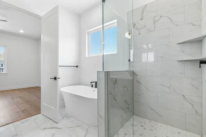 Bathroom featuring light marble finish floors, a freestanding tub, and a marble finish shower