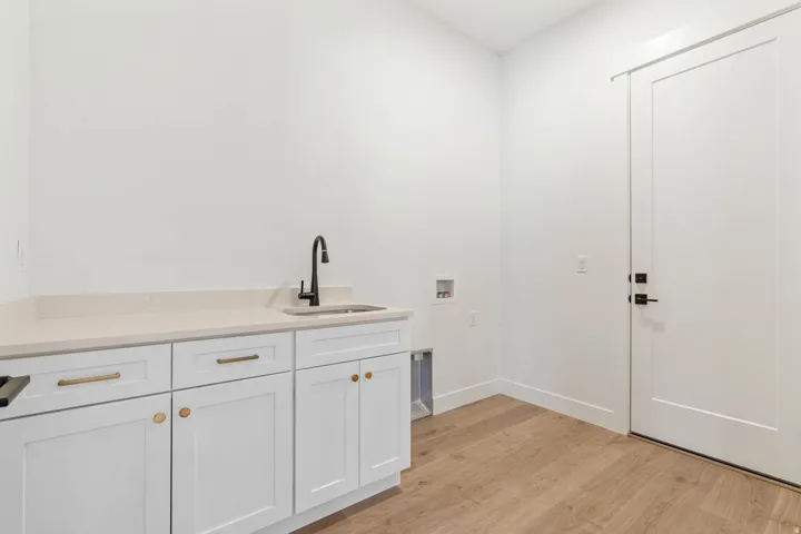 Laundry room with light wood-style flooring, washer hookup, and cabinet space