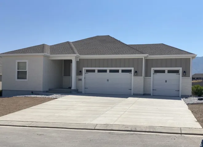 View of front facade featuring a garage, a shingled roof, driveway, and brick siding
