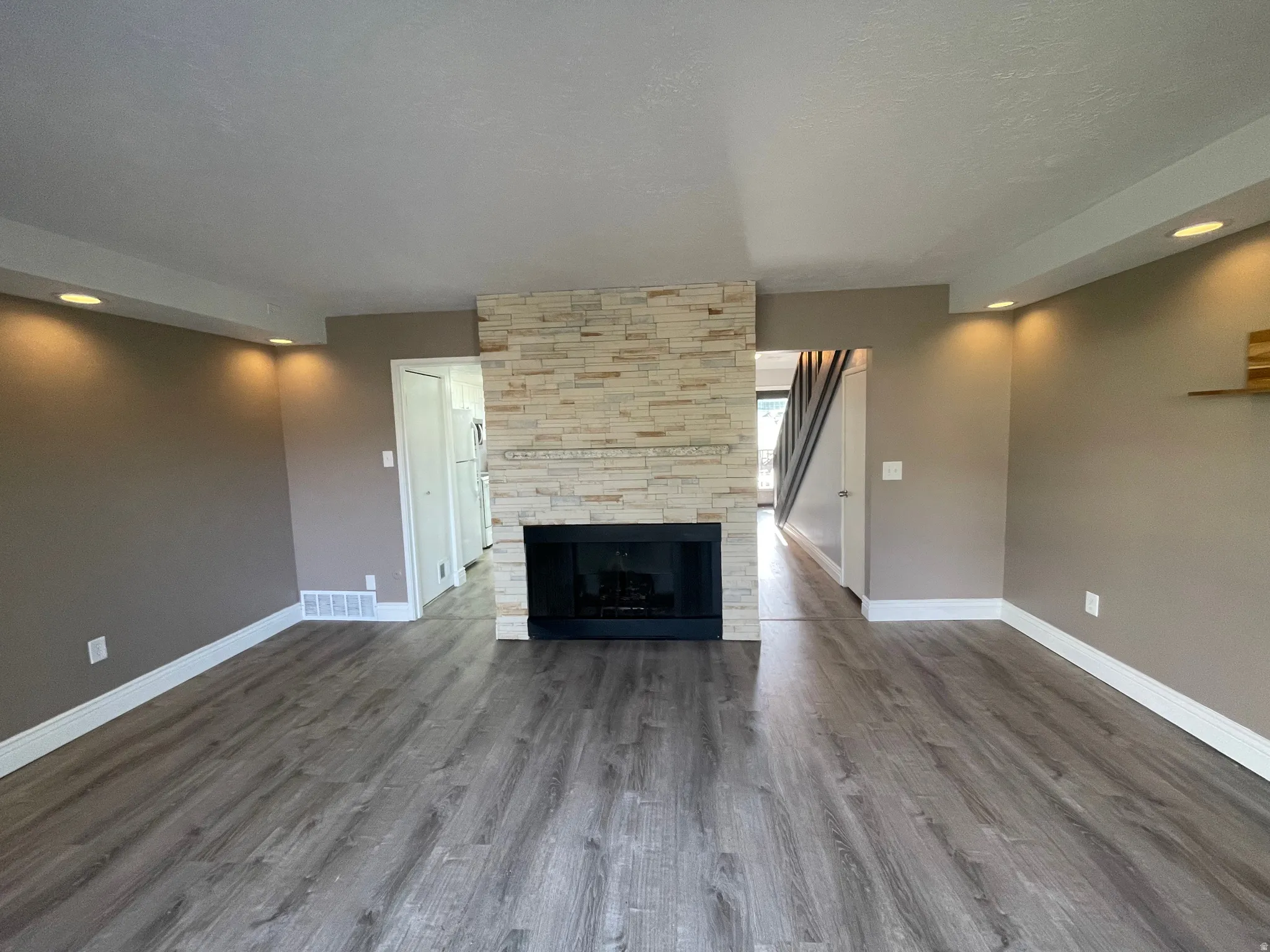 Unfurnished living room with grand floor-to-ceiling fireplace, recessed lighting, dark wood-style floors, and a textured ceiling