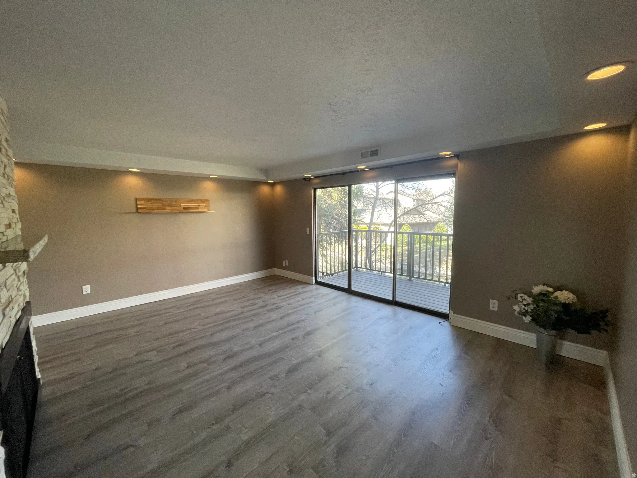Grand living room featuring recessed lighting, dark wood finished floors, triple sliding door with fabulous views and an up-to-date stone fireplace